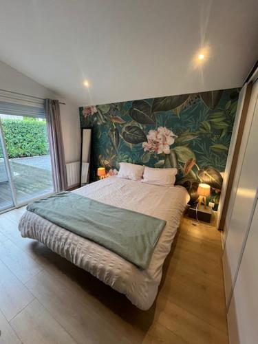 1 dormitorio con 1 cama grande y pared de flores en Jolie maison Ares, en Arès