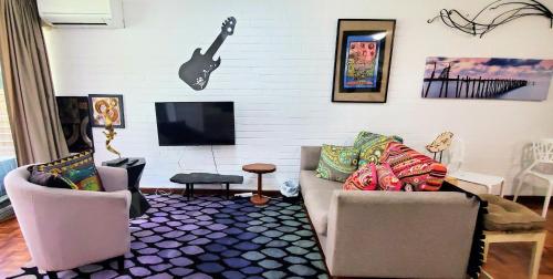 a living room with two chairs and a guitar on the wall at Quaint & Tranquil Subiaco 1 Bedroom Apartment in Perth