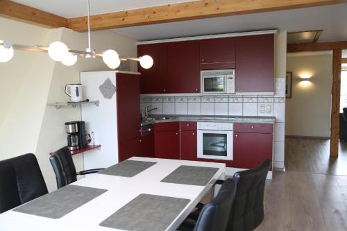 シャルボイツにあるGästehaus Daheimのキッチン(赤いキャビネット、テーブル、椅子付)