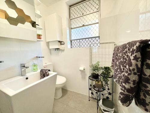 a bathroom with a sink and a toilet and a window at Serenity And Comfort In Subiaco 1 Bedroom Unit in Perth