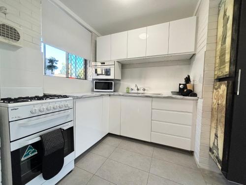 a white kitchen with a stove and a sink at Serenity and Comfort in Subiaco 1 Bedroom Unit in Perth