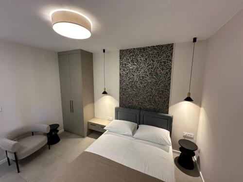 a bedroom with a white bed and a chair at Apartment & Room IRIS in Zadar