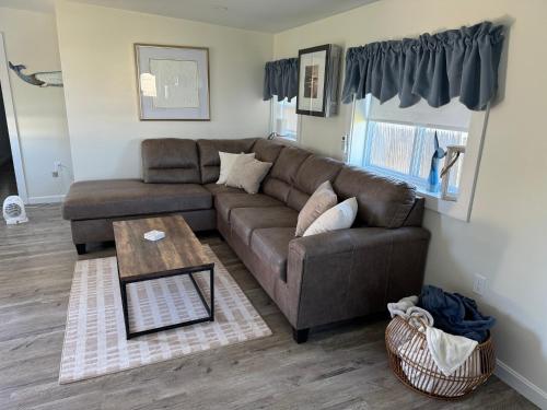 ein Wohnzimmer mit einem braunen Sofa und einem Tisch in der Unterkunft Quaint, family friendly Beach house for 4 in South Dartmouth