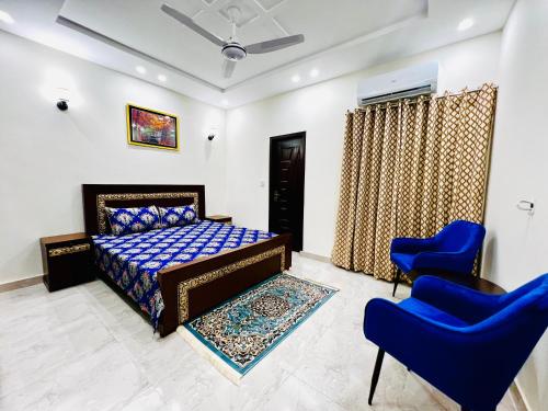 a bedroom with a bed and two blue chairs at Sj Luxury Suits in Lahore