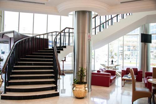 a spiral staircase in a lobby with red chairs at Dubai Grand Hotel by Fortune, Dubai Airport in Dubai