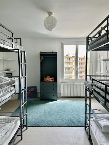 une chambre avec trois lits superposés et un tapis bleu dans l'établissement La Mer à Pied appartement vue mer, à Dieppe