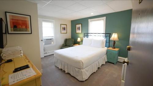 a bedroom with a white bed and a green wall at North Beach Hotel in Ventnor City