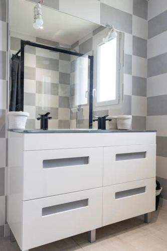 une salle de bain blanche avec un lavabo et un miroir dans l'établissement Maison ambiance COSY - Détente - Clim - 3 chambres, à Allez-et-Cazeneuve