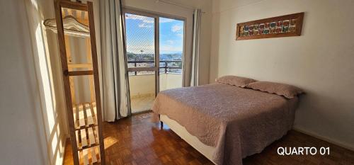a bedroom with a bed and a large window at Centro Guarapari - espaço & conforto - WI-FI in Guarapari