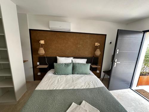 um quarto com uma cama com duas almofadas verdes em La maison d'HamiH "Gîte et Chambres d'hôtes em Uzès