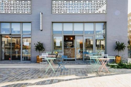 a store with tables and chairs in front of a building at Peaceful green setting near to Paris Center in Pantin