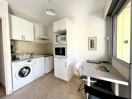- une cuisine blanche avec un lave-linge et une table dans l'établissement Mandelieu Studio rez-de-jardin à Cannes Marina, à Mandelieu-la-Napoule