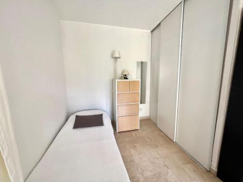 une chambre blanche avec un lit et une commode dans l'établissement Mandelieu Studio rez-de-jardin à Cannes Marina, à Mandelieu-la-Napoule