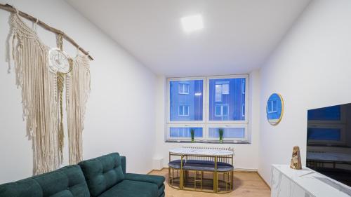 a living room with a green couch and a window at Spirit apartments Brno, with parking in Brno