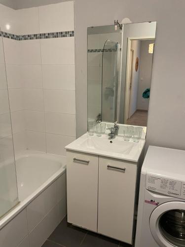 La salle de bains est pourvue d'un lavabo, d'une baignoire et d'un lave-linge. dans l'établissement Appartement 2 chambres avec terrasse et garage, à Saint-André