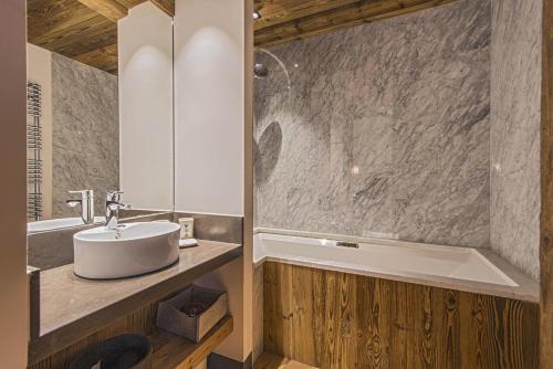 une salle de bain avec un lavabo et une baignoire dans l'établissement Penthouse Le Savoie - LES CHALETS COVAREL, à Val dʼIsère