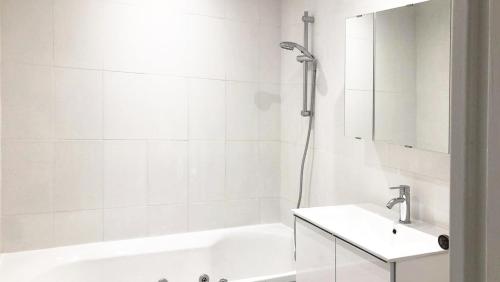 une salle de bain blanche avec une baignoire et un lavabo dans l'établissement Appartement verdoyant, à Noisy-le-Grand
