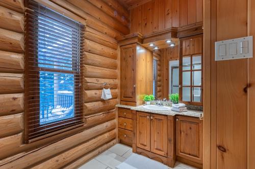 Cabaña de madera con lavabo y ventana en Fiddler Lake Resort Chalet 48 Deer, en Mille-Isles