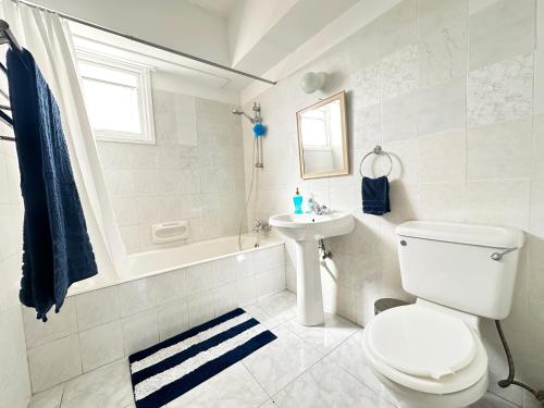 a white bathroom with a toilet and a sink at Serenity Sunrise Holiday Apt - Larnaca in Larnaka
