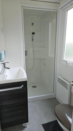 une salle de bain blanche avec une douche et un lavabo dans l'établissement Spacieux Mobil-home Num227 2 chambres, 2sdb à 2 pas du lac, à Gastes