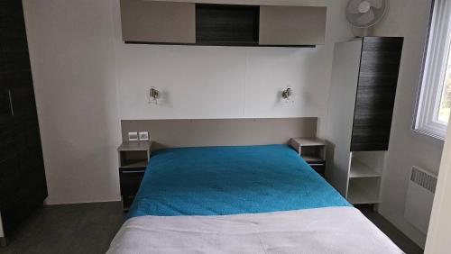 une chambre avec un lit avec une couverture bleue dans l'établissement Spacieux Mobil-home Num227 2 chambres, 2sdb à 2 pas du lac, à Gastes