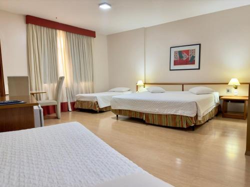 um quarto de hotel com duas camas e uma secretária em César Park Hotel em Juiz de Fora