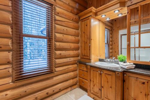 a log cabin bathroom with a sink and a window at Fiddler Lake Resort Chalet 53 Cerf in Mille-Isles