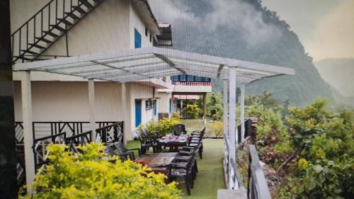 une terrasse avec une table et des chaises devant un bâtiment dans l'établissement Baandal River Resort Maldevta, à Kokliyal Gaon