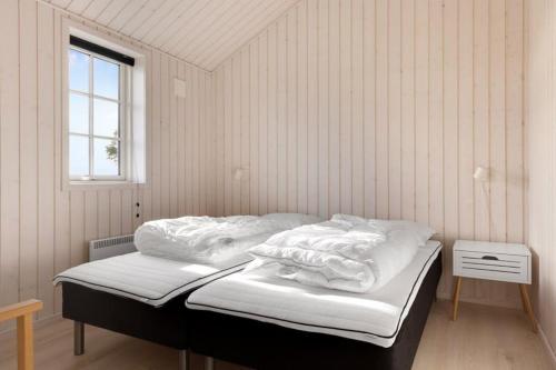 a bedroom with a bed with white sheets and a window at Havnsø med udsigt in Føllenslev