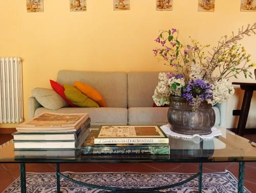 una mesa de centro con libros y un jarrón con flores. en Podere Casato, en Montespertoli