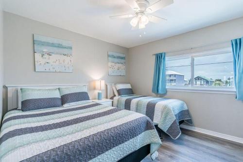 Duas camas num quarto com cortinas azuis e uma janela. em Bonhomme Richard West em Gulf Shores