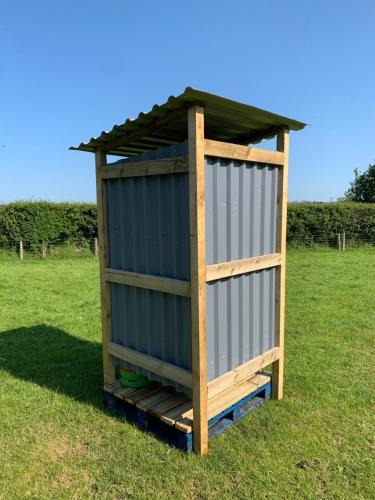 a wooden outhouse with a roof on a grass field at Rescorla Retreats - Patsy in St Austell