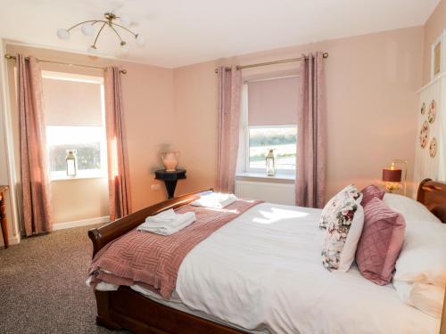 a bedroom with a large bed with two windows at Smithy House in Dumfries
