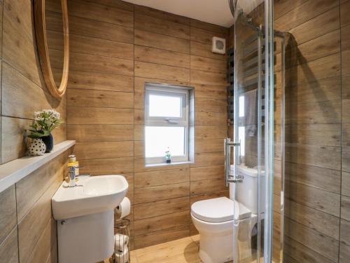 a bathroom with wooden walls and a toilet and a sink at Smithy House in Dumfries