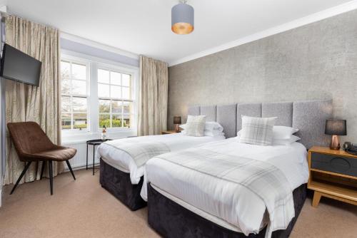 a bedroom with two beds and a chair at Dornoch Castle Hotel in Dornoch