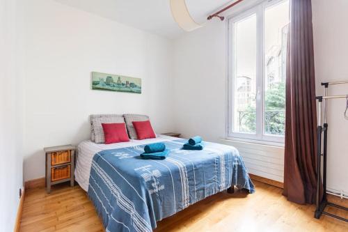 a bedroom with a bed with a blue blanket and a window at Bel appartement aux portes de Paris in Cachan