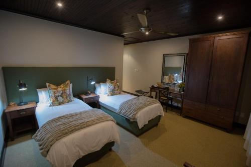 a bedroom with two beds and a mirror at Swartberg Private Game Lodge in Oudtshoorn