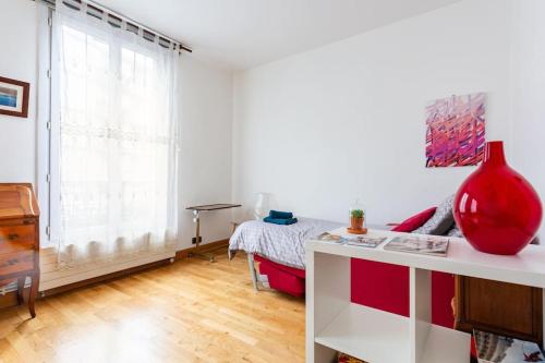 a white room with a red vase on a desk at Bel appartement aux portes de Paris in Cachan