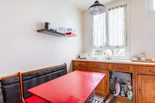 a kitchen with a red table and a sink at Bel appartement aux portes de Paris in Cachan