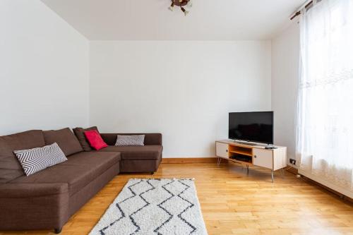 a living room with a couch and a flat screen tv at Bel appartement aux portes de Paris in Cachan