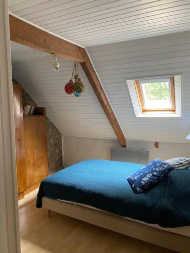 - une chambre mansardée avec un lit bleu dans l'établissement Ty Manine, à Brélidy