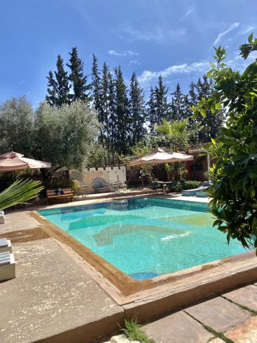 a swimming pool with blue water in a yard at AL MAQAM ATAQAFI in Tahannout