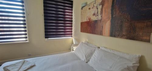 a bedroom with a bed with white pillows and a painting at Mermaid Suite Hotel in London