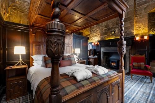 een slaapkamer met een hemelbed en een open haard bij Dornoch Castle Hotel in Dornoch