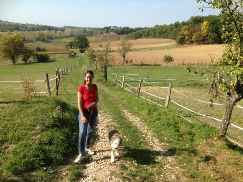 a woman standing on a dirt road with a dog at Puechblanc Gîtes et Chambre d'hôte dans le Triangle d'or Gaillac-Albi-Cordes sur Ciel in Fayssac