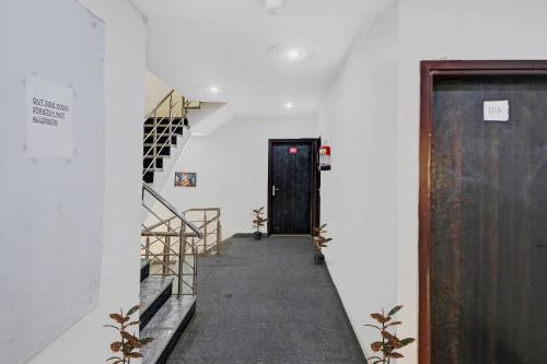 un couloir avec une porte noire et des escaliers dans l'établissement OYO Hotel Lotus, à New Delhi