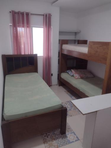 Cette petite chambre comprend 2 lits superposés et une fenêtre. dans l'établissement Apartamento espaçoso, à Cabo Frio