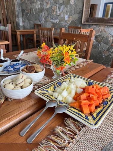 a wooden table with a plate of food and vegetables at Pousada Pouso de Laura in Tiradentes