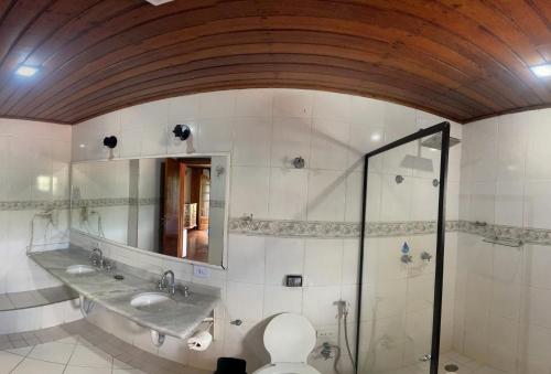 a bathroom with a shower and a toilet and a mirror at Pousada Atalaia Capivari in Campos do Jordão