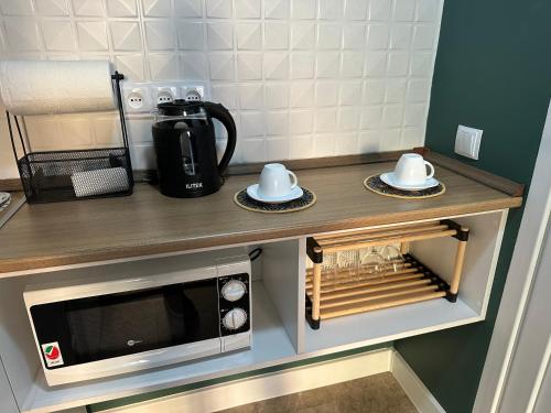 a kitchen counter with a microwave and two dishes at City Centre Apartment - Mari in Kutaisi